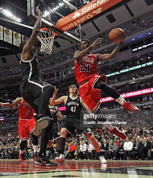 Jimmy Butler of the Chicago Bulls leaps to pass around Andray Blatche of the Brooklyn Nets at the United Center on February 13, 2014 in Chicago,...