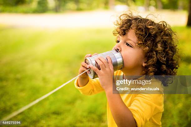 african american boy talking into tin can phone in park - kids talking through cans stock pictures, royalty-free photos & images