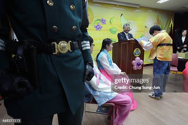 Graduate of Taesungdong Elementary School Yang Kyu-Bin receive a graduation certificate as a South Korean soldier escorts during the graduation...