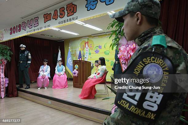 Graduate of Taesungdong Elementary School students attend as a South Korean soldiers escort them during the graduation ceremony on February 14, 2014...