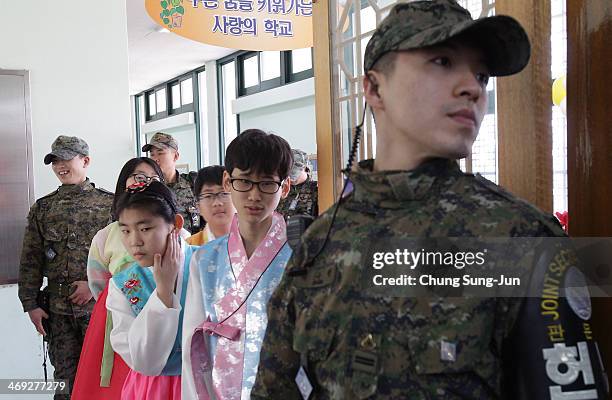 Graduate of Taesungdong Elementary School students attend as a South Korean soldiers escort them during the graduation ceremony on February 14, 2014...