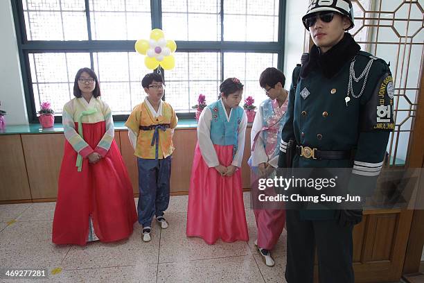 Graduate of Taesungdong Elementary School students attend as a South Korean soldiers escort them during the graduation ceremony on February 14, 2014...