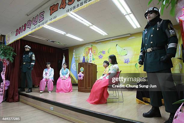 Graduate of Taesungdong Elementary School students attend as a South Korean soldiers escort them during the graduation ceremony on February 14, 2014...