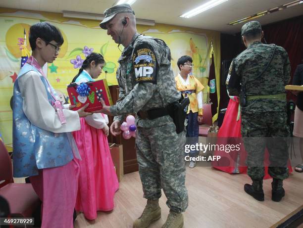 Graduate Kwon Jong-hyuck of Taesungdong Elementary School receives a present from US Army LTC Daniel Edwan during a graduation ceremony at...