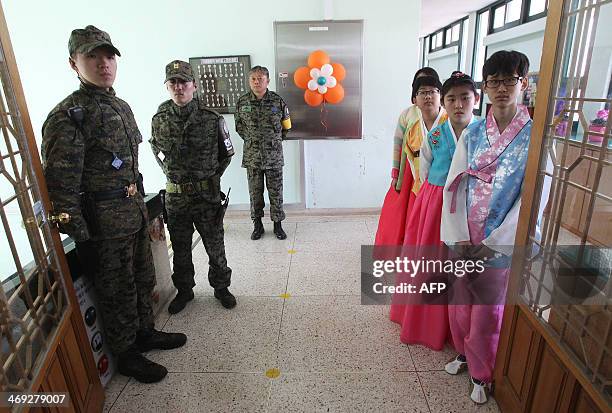 Graduates wearing traditional dress stand next to military officers during a graduation ceremony for Taesungdong Elementary School at Taesungdong...