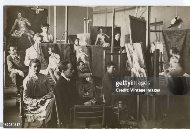 Group of artists and a nude model in a life painting class, circa 1920.