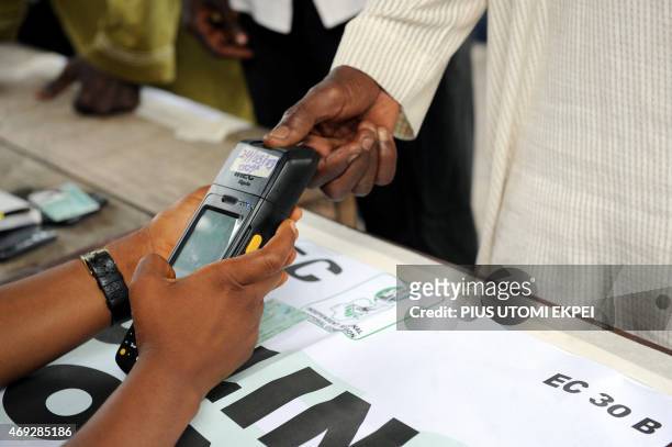 An official of Independent National Electoral Commission registers thumb print of a voter with biometric system at a polling station at Apapa...