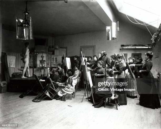 Naked man poses for a roomful of ladies at a life drawing class, circa 1900.