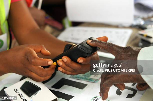 An official of Independent National Electoral Commission registers the finger print of a voter with biometric system at a polling station at Apapa...