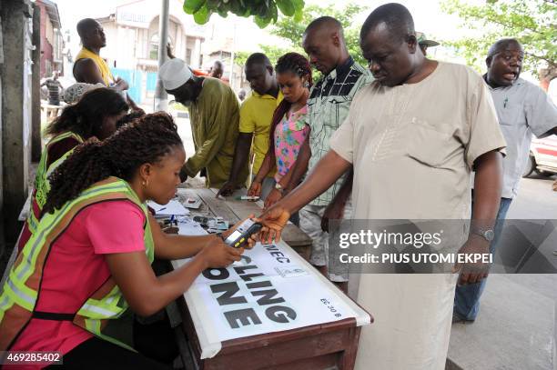 An official of Independent National Electoral Commission registers the thumb print of a voter with biometric system at a polling station at Apapa...