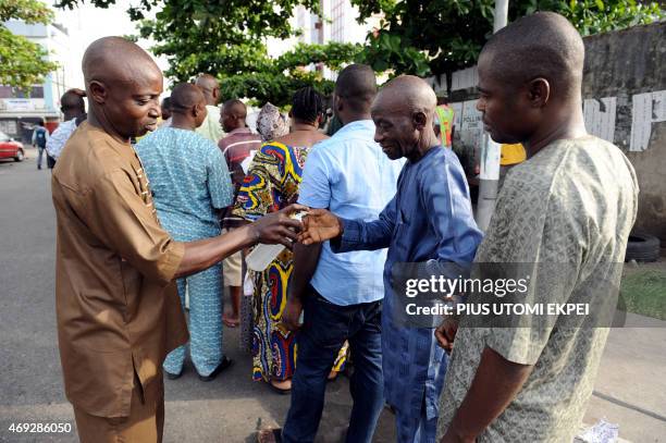 An official of the Independent National Electoral Commission distributes a cleansing fluid for voters to clean their thumbs to facilitate thumb...