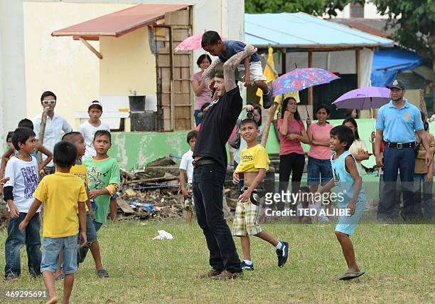England football superstar David Beckham carries a boy on his shoulders during a football game with children-survivors of super Typhoon-Haiyan at a...