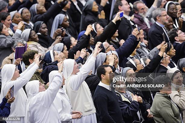 Nuns take pictures as Pope Francis waving to members of the Istituti di Vita Consacrata and Società di Vita Apostolica at the end of a meeting in...