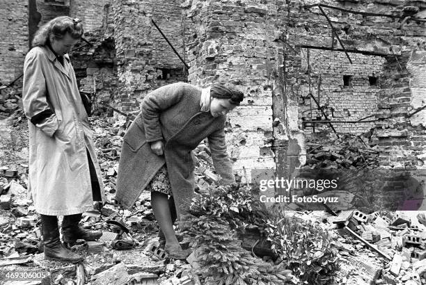 Europe, Poland, 1940s: Liberation of Warsaw, Women placing a wreath, Buildings damaged after intensive bombing raid.