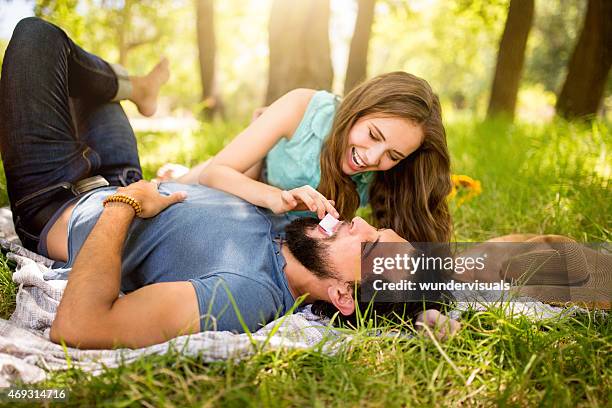 mädchen spielerisch füttern ihrem freund schokolade in einem park - couple chocolate stock-fotos und bilder