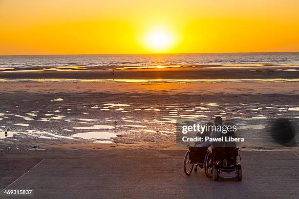 Disabled couple on wheelchairs watching Sunset over Blackpool Beach at Low Tide.