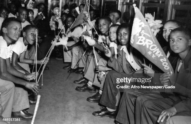 Large group of boys sitting in a subway carriage, holding Bronx Zoo pennants, New York, New York, 1960.
