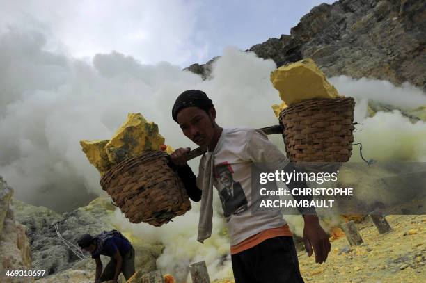This photo taken on December 25, 2010 shows an Indonesian miner carrying baskets of sulphur from the bottom of the crater of Indonesia's active Kajah...