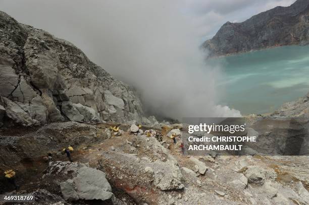 This photo taken on December 25, 2010 shows Indonesian miners carrying baskets of sulphur from the bottom of the crater of Indonesia's active Kajah...