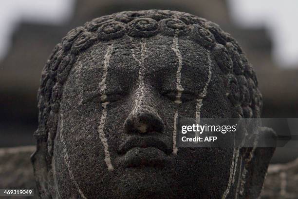 Stone figure of buddha at the ancient Borobudur temple in Central Java is smeared with volcanic ash on February 14, 2014 following the eruption of...