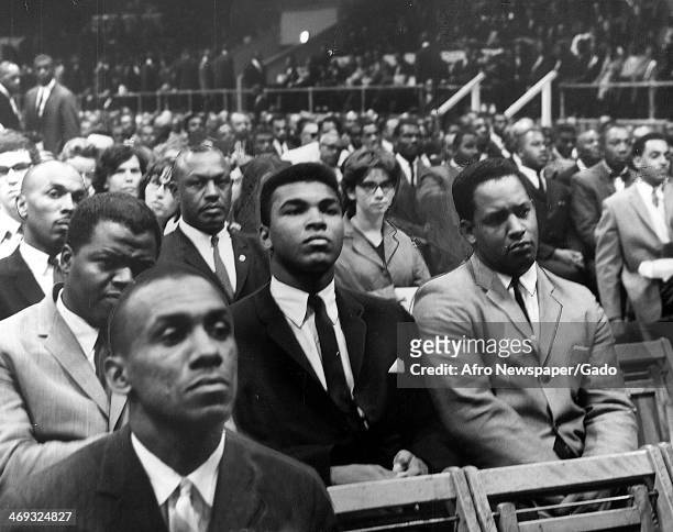Cassius Clay, heavyweight boxing contender, listens to Elijah Muhammad, the leader of the group Nation of Islam, speaking at a rally prior to Elijah...