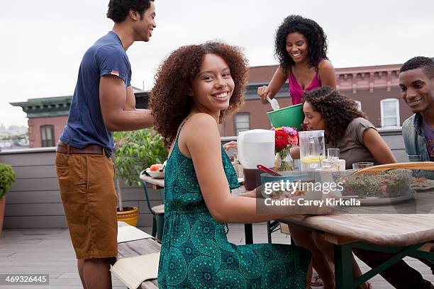 young woman sitting at a picnic table with friends - long table stock pictures, royalty-free photos & images