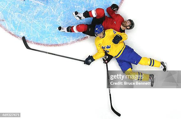 Julien Vauclair of Switzerland falls to the ice with Jimmie Ericsson in the first period during the Men's Ice Hockey Preliminary Round Group C game...