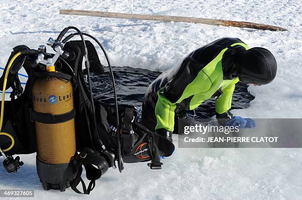 An ice diving client gets out of a hole in the frozen Lake of Tignes 100 meters high, in the French Alps, on February 11, 2014. Ice diving is now...