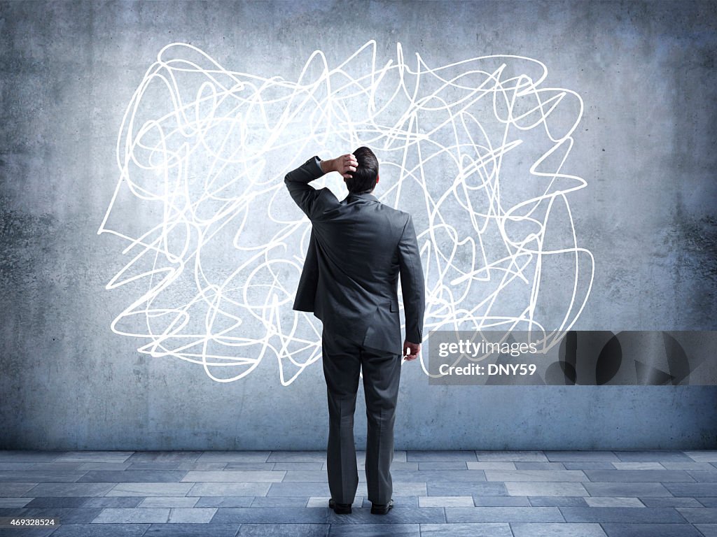 Confused businessman staring at scribble on wall