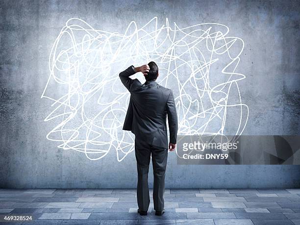 confused businessman staring at scribble on wall - ingewikkeldheid stockfoto's en -beelden
