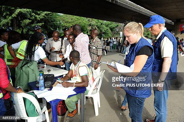 European Union observers take notes as officials of Independent National Electoral Commission count ballots during gubernatorial and local assembly...