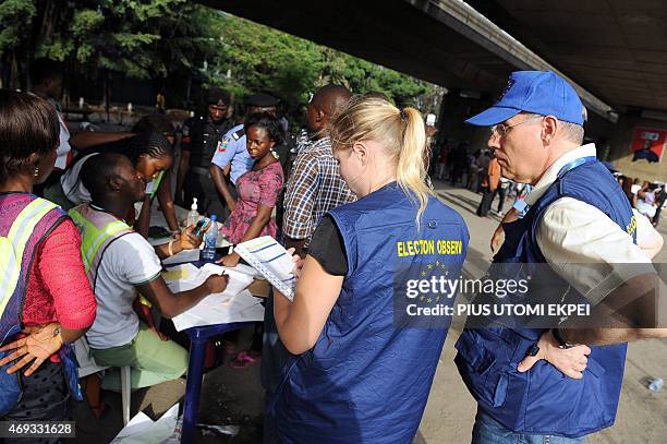 European Union observers take notes as officials of Independent National Electoral Commission count ballots during gubernatorial and local assembly...