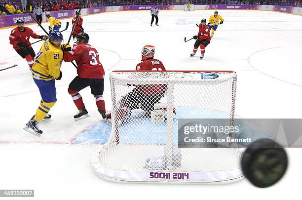 Loui Eriksson of Sweden and Mathias Seger of Switzerland fight for position as a puck flies along the glass in the second period during the Men's Ice...