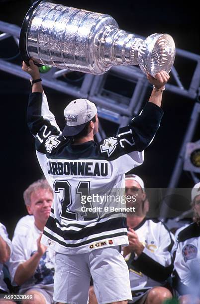 Guy Carbonneau of the Dallas Stars holds aloft the Stanley Cup Trophy during the Stars parade after they defeated the Buffalo Sabres in six games to...