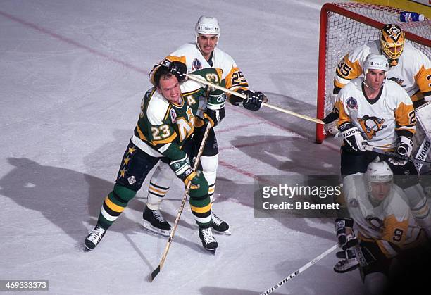Brian Bellows of the Minnesota North Stars has his helmet knocked off as he battles for position with Kevin Stevens of the Pittsburgh Penguins during...