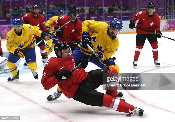 Mathias Seger of Switzerland falls while handling the puck against Marcus Johansson of Sweden in the third period during the Men's Ice Hockey...
