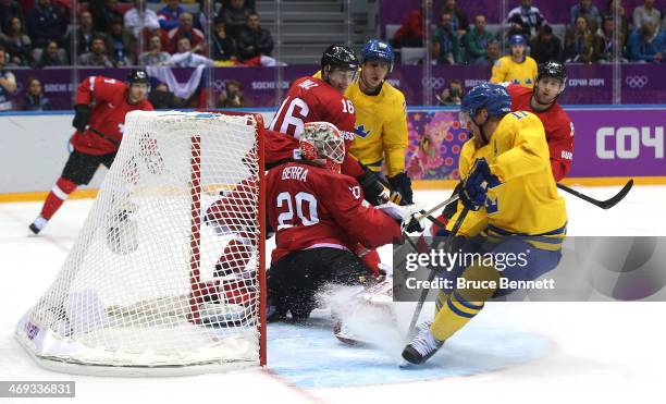 Daniel Alfredsson of Sweden shoots and scores against Reto Berra of Switzerland in the third period during the Men's Ice Hockey Preliminary Round...