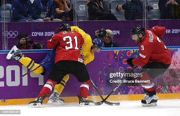 Loui Eriksson of Sweden is hit into the boards by Mathias Seger of Switzerland in the third period during the Men's Ice Hockey Preliminary Round...