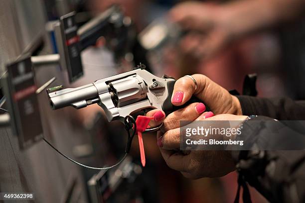 Attendees look over hand guns in the Smith & Wesson booth on the exhibition floor of the 144th National Rifle Association Annual Meetings and...