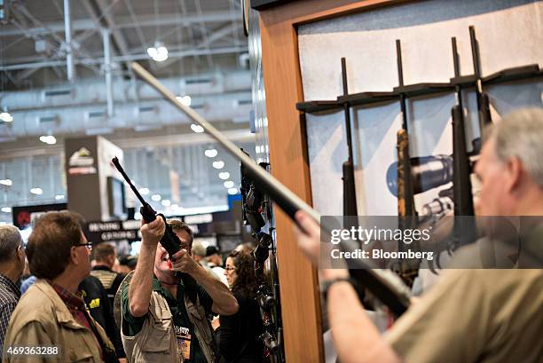 Attendees look over items in the Remington Arms Co. LLC booth on the exhibition floor of the 144th National Rifle Association Annual Meetings and...