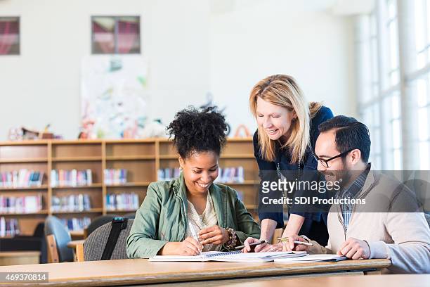 diverse study group of adults working in large college library - teacher stock pictures, royalty-free photos & images