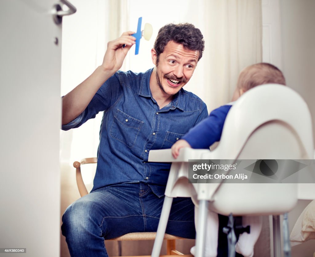 Father feeding baby in high chair