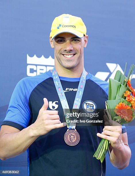 Bronze medal winner Joao de Lucca celebrates on the podium after swimming in the Men's 100m freestyle final on day six of the Maria Lenk Swimming...