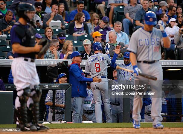 Chris Coghlan of the Chicago Cubs is welcomed to the dugout by manager Joe Maddon of the Chicago Cubs and Dave Martinez of the Chicago Cubs after his...