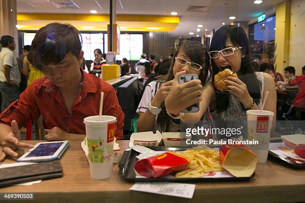 Vietnamese girls takes photos of themselves eating at the new McDonald's restaurant February 14, 2014 in Ho Chi Minh City, Vietnam. The first...