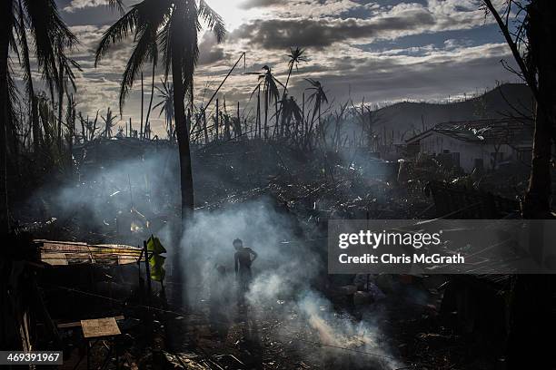 Man throws debris onto a fire as he cleans up his home in Tanauan on November 19, 2013 in Leyte, Philippines. Typhoon Haiyan, which ripped through...