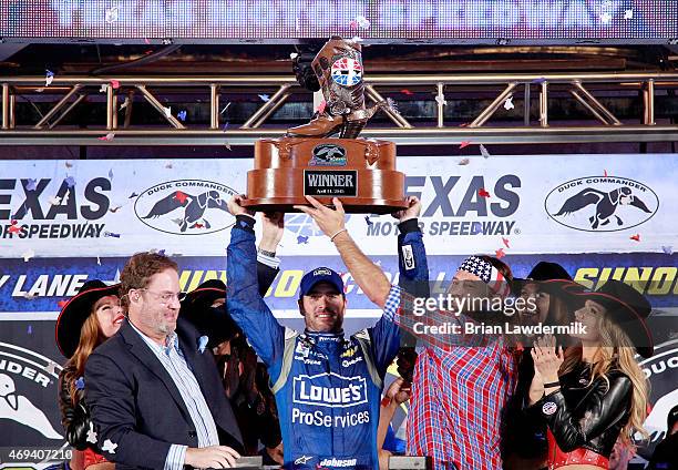 Jimmie Johnson, driver of the Lowe's Pro Services Chevrolet, raises the winners trophy in Victory Lane after winning the NASCAR Sprint Cup Series...