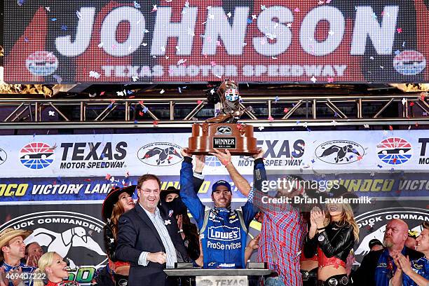 Jimmie Johnson, driver of the Lowe's Pro Services Chevrolet, raises the winners trophy in Victory Lane after winning the NASCAR Sprint Cup Series...