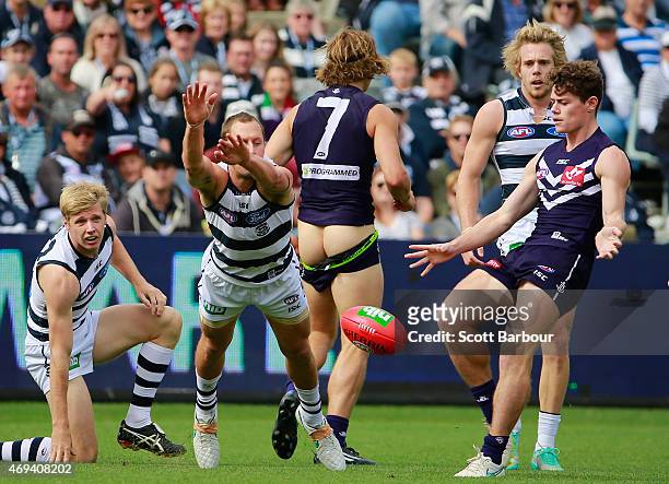 Lachie Neale of the Dockers kicks the ball as Nathan Fyfe of the Dockers loses his shorts during the round two AFL match between the Geelong Cats and...