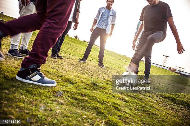 junge menschen spielen fußball im park - street football stock-fotos und bilder